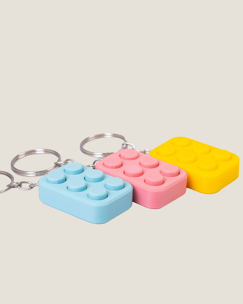 3D printed bubble pop clicker keychains in pink, yellow and blue