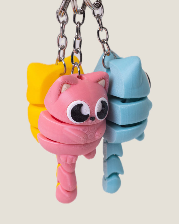 3D printed flexi cat keychains in pink, yellow and blue