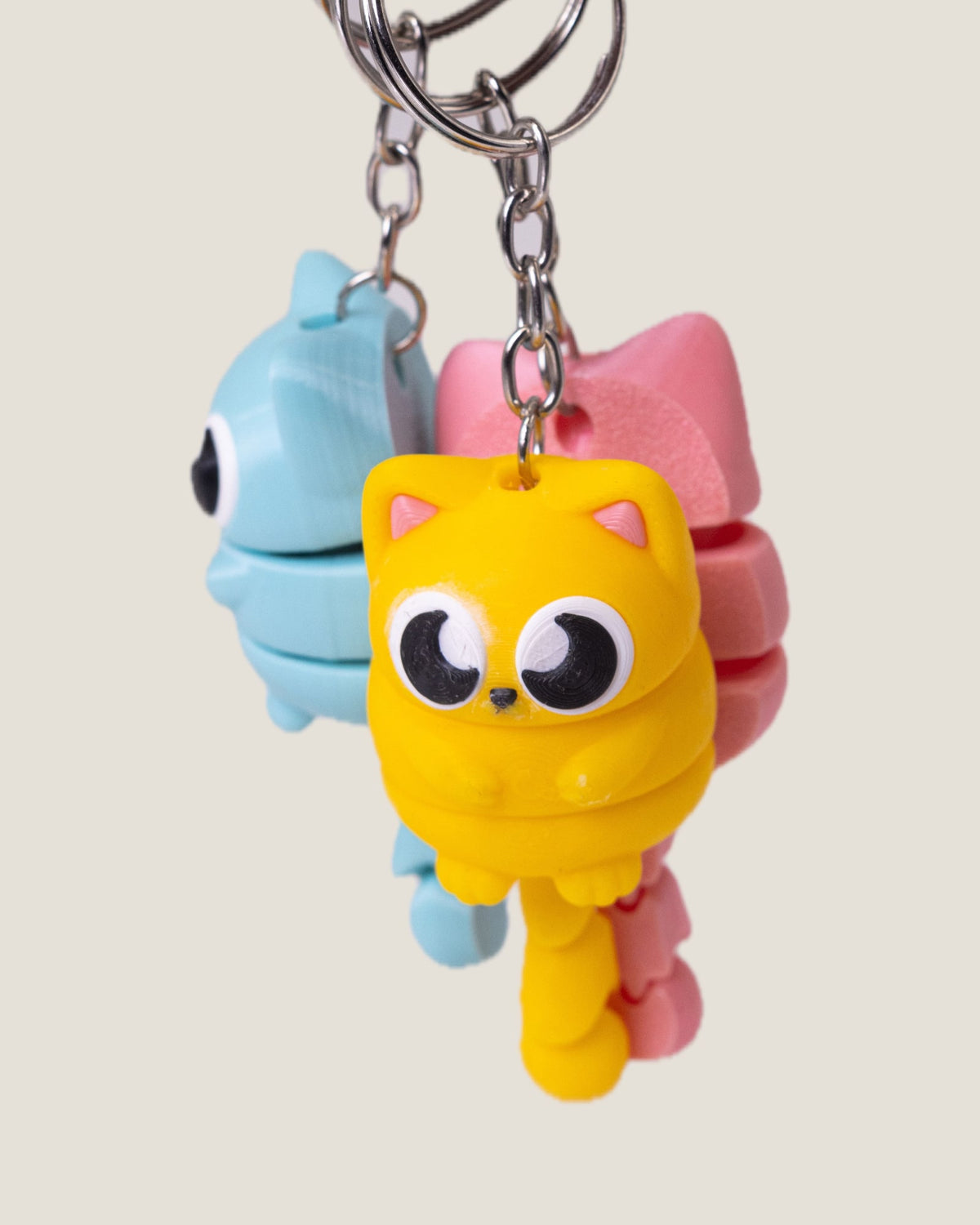 3D printed flexi cat keychains in pink, yellow and blue