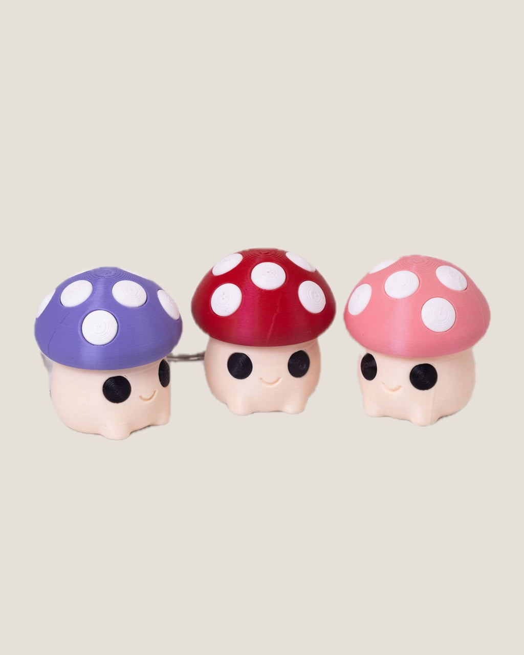 3D printed mushroom clicker keychains in purple, red and pink