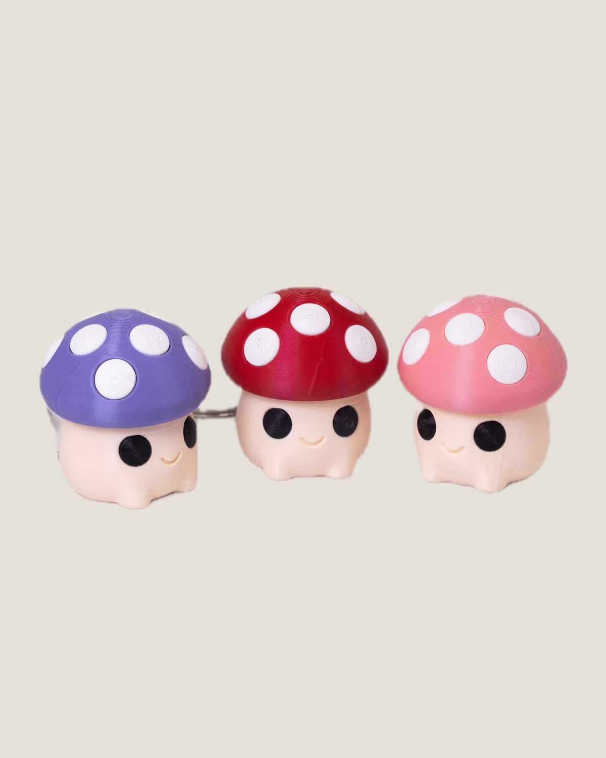 3D printed mushroom clicker keychains in purple, red and pink